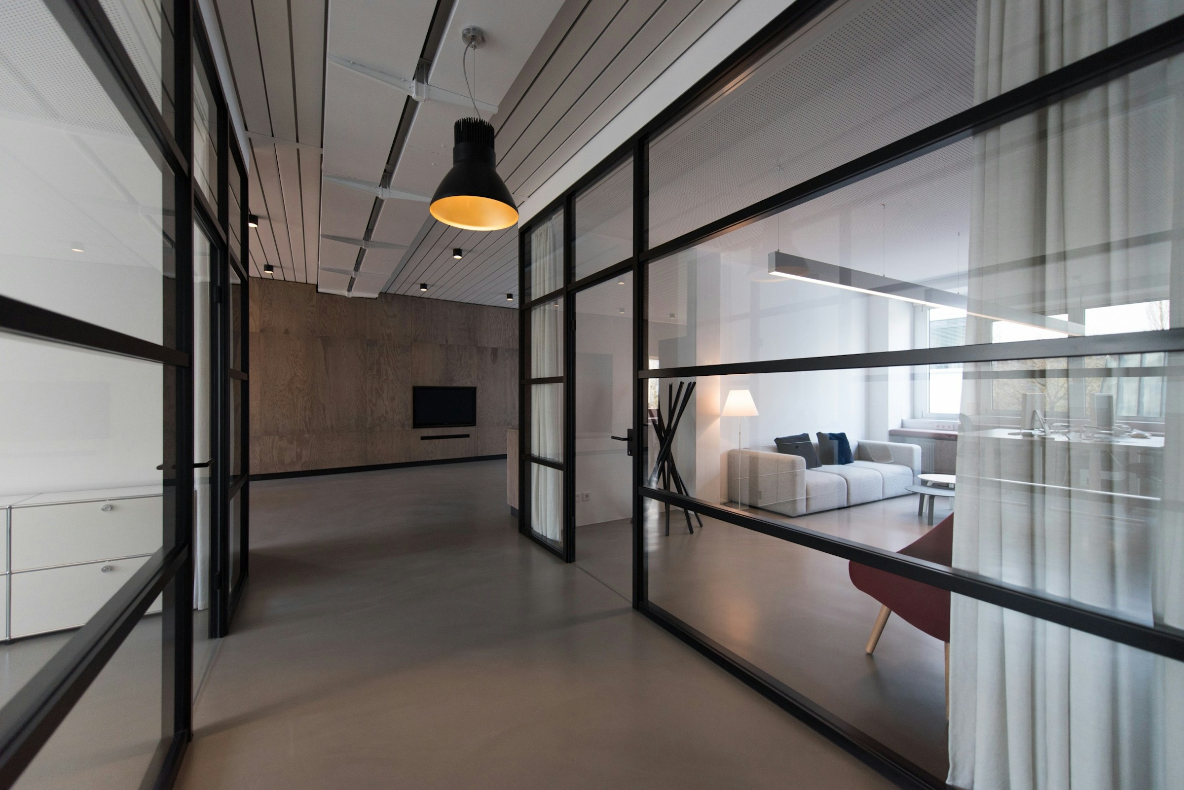 Glass-walled studio room with lounge seating and soft curtains